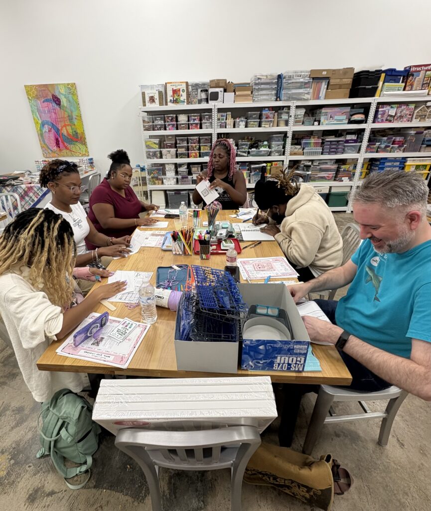 A group of people sitting around a table, working on crafts.