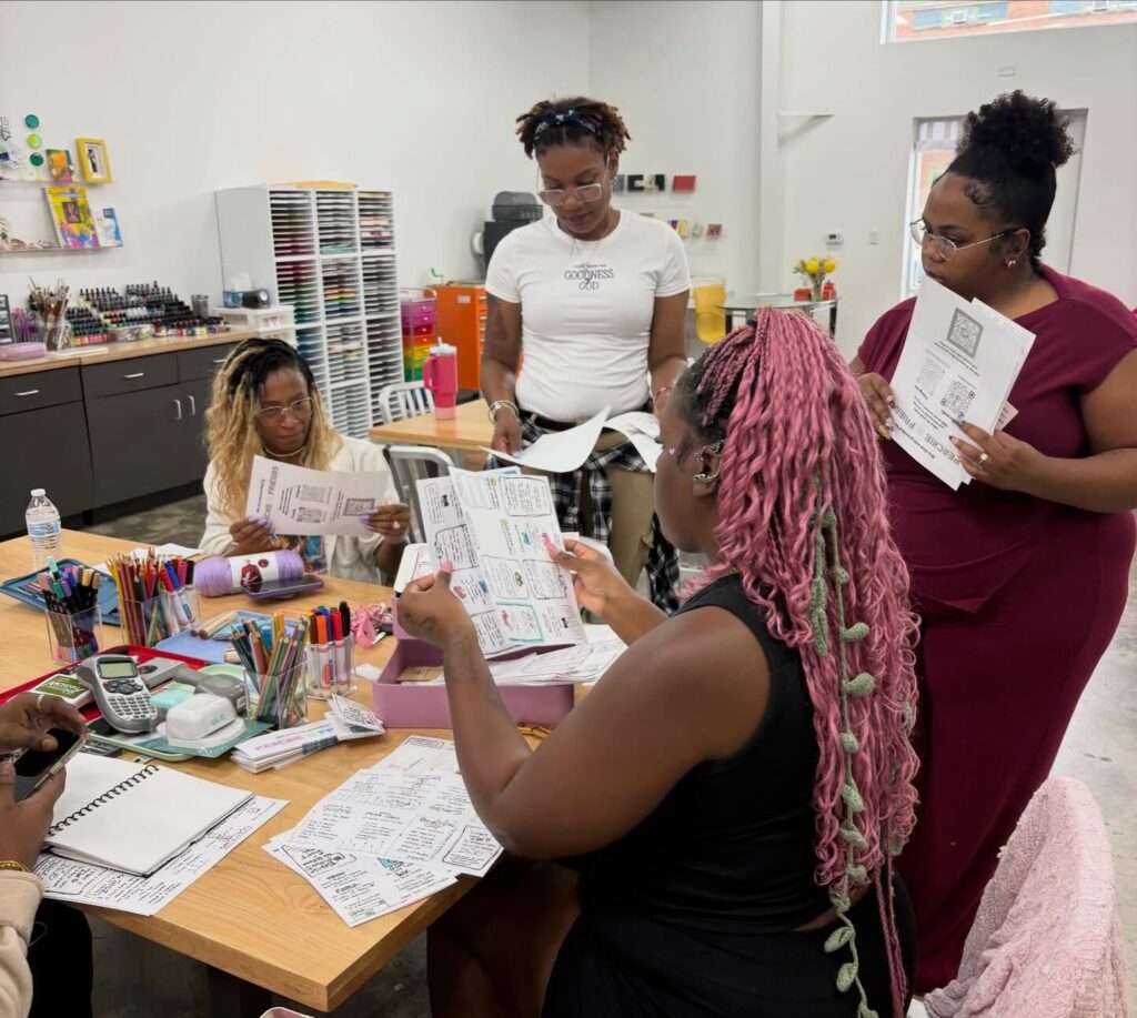 A group of people sitting around a table, working on crafts.