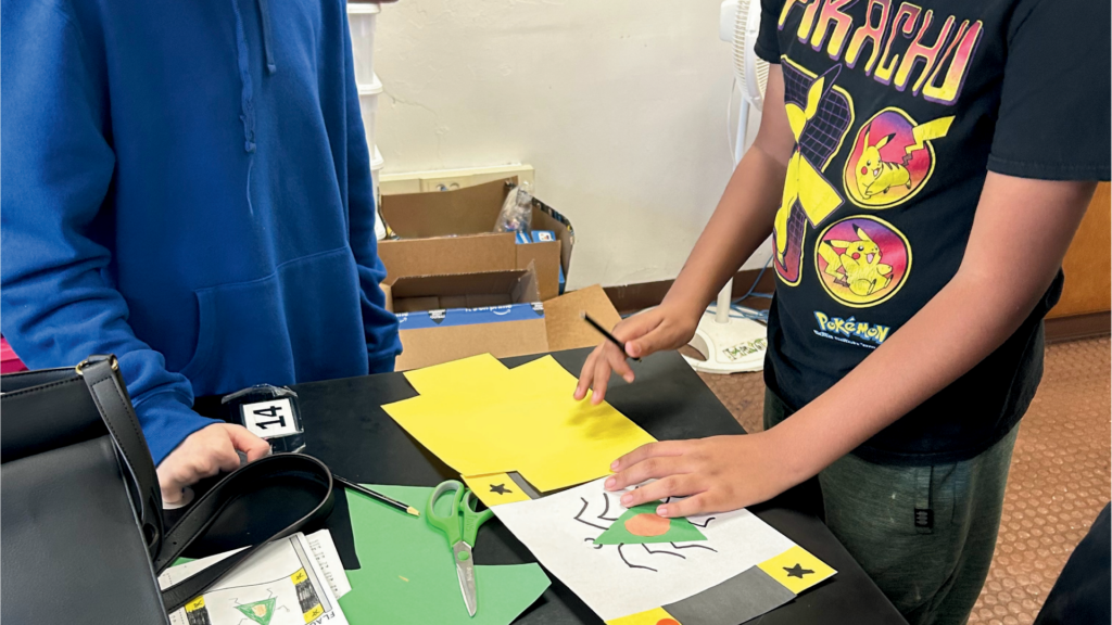 Two middle school boys stand around a table working on a science assignment.